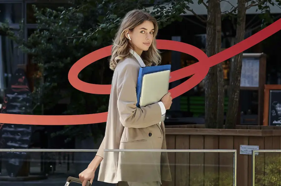 Business traveler in professional attire carrying laptop and rolling suitcase